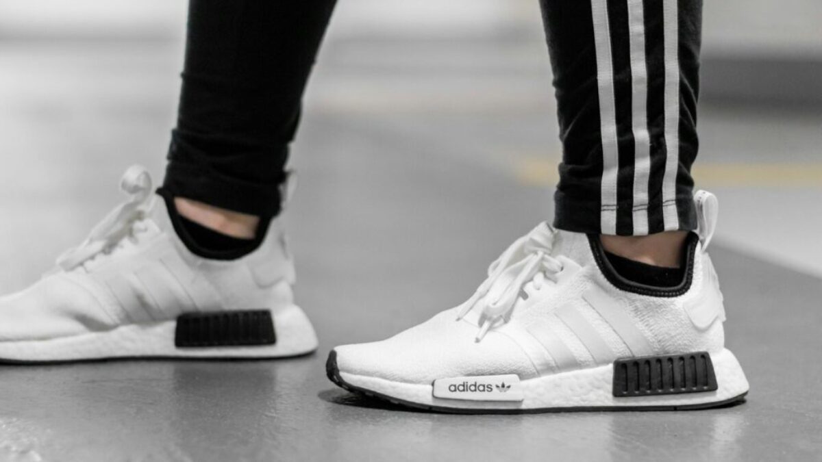 person wearing white Adidas NMD shoes