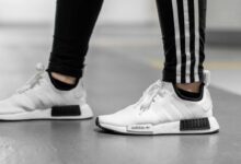 person wearing white Adidas NMD shoes