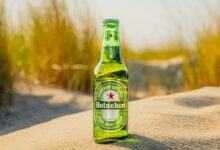 a bottle of beer sitting on top of a sandy beach