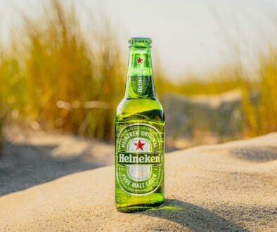 a bottle of beer sitting on top of a sandy beach