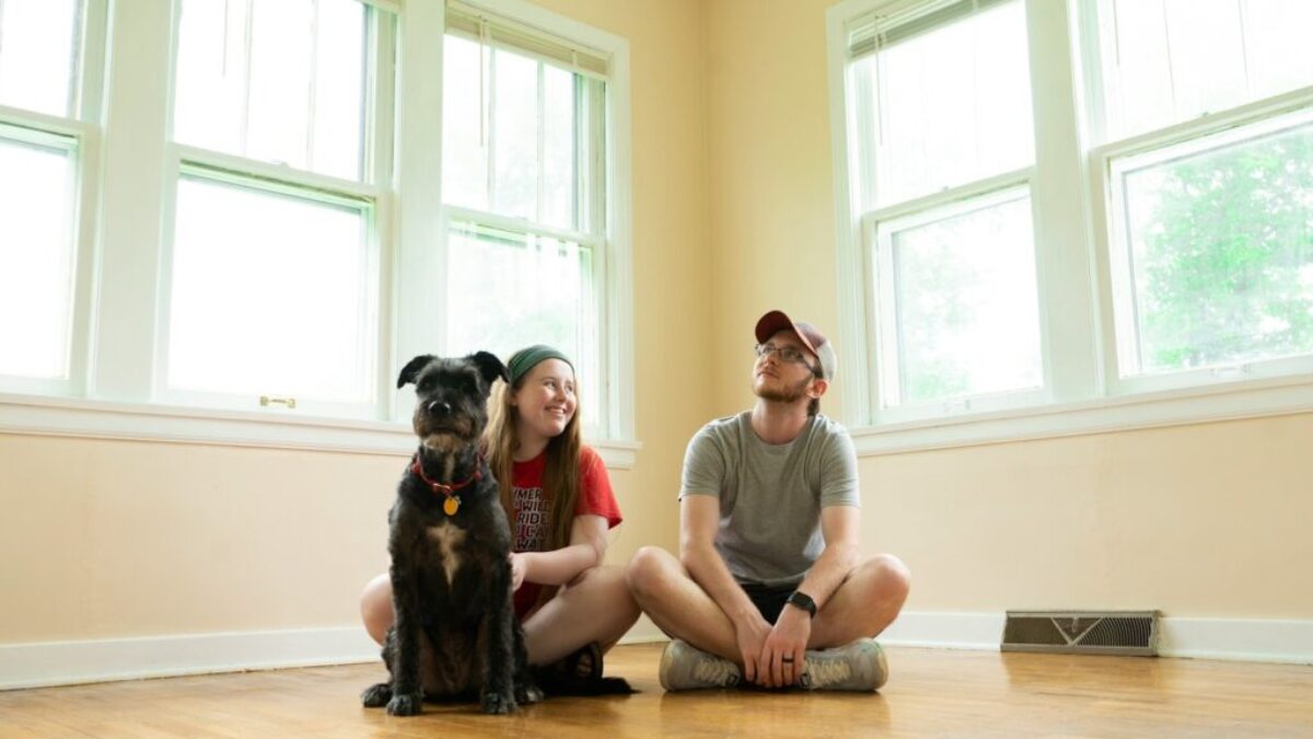 woman in gray shirt sitting on brown wooden floor