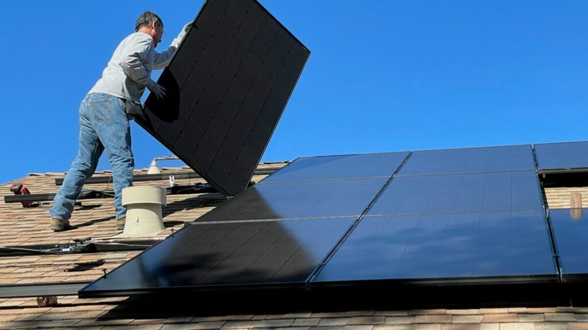 man in white dress shirt and blue denim jeans sitting on white and black solar panel