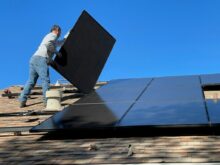 man in white dress shirt and blue denim jeans sitting on white and black solar panel
