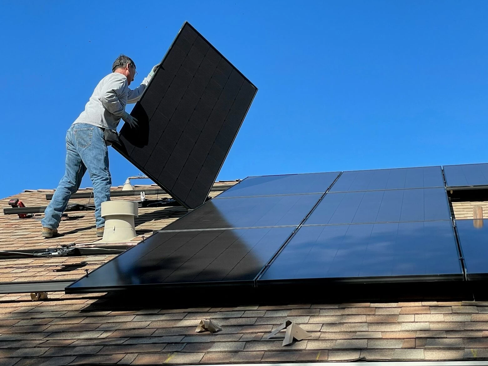 man in white dress shirt and blue denim jeans sitting on white and black solar panel