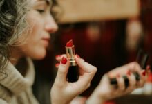 woman in gray sweater holding lipstick