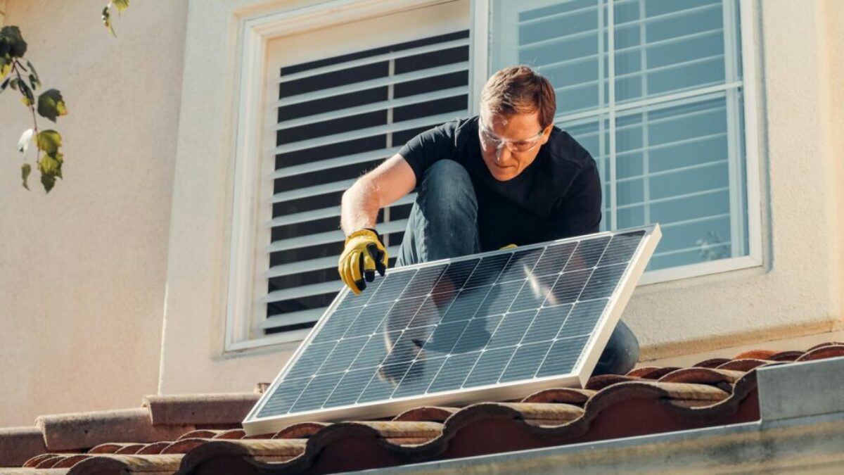 Solar technician installing a photovoltaic panel on a rooftop, promoting renewable energy.