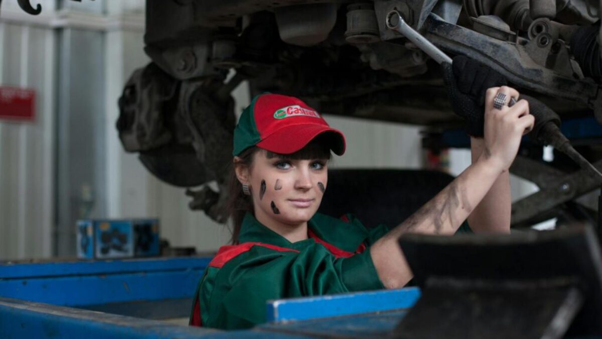 Female mechanic maintaining a car in an auto repair shop, showcasing skill and concentration.