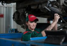 Female mechanic maintaining a car in an auto repair shop, showcasing skill and concentration.