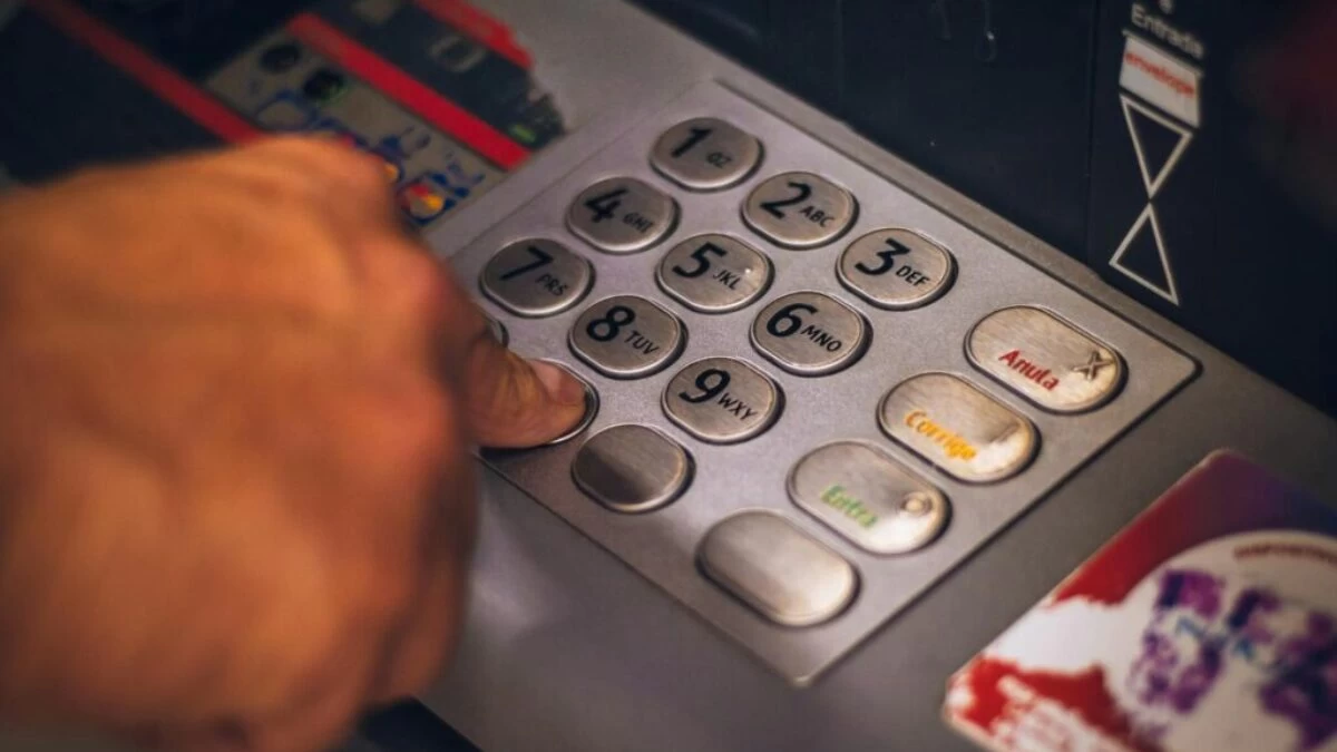 A hand pressing a button on an ATM keypad in Brasil, emphasizing digital banking.