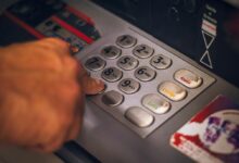 A hand pressing a button on an ATM keypad in Brasil, emphasizing digital banking.
