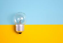 A clear light bulb against a vibrant blue and yellow background, symbolizing energy and creativity.