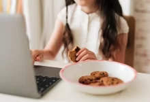 Žena hledá informace na internetu a současně jí sušenky, cookies.