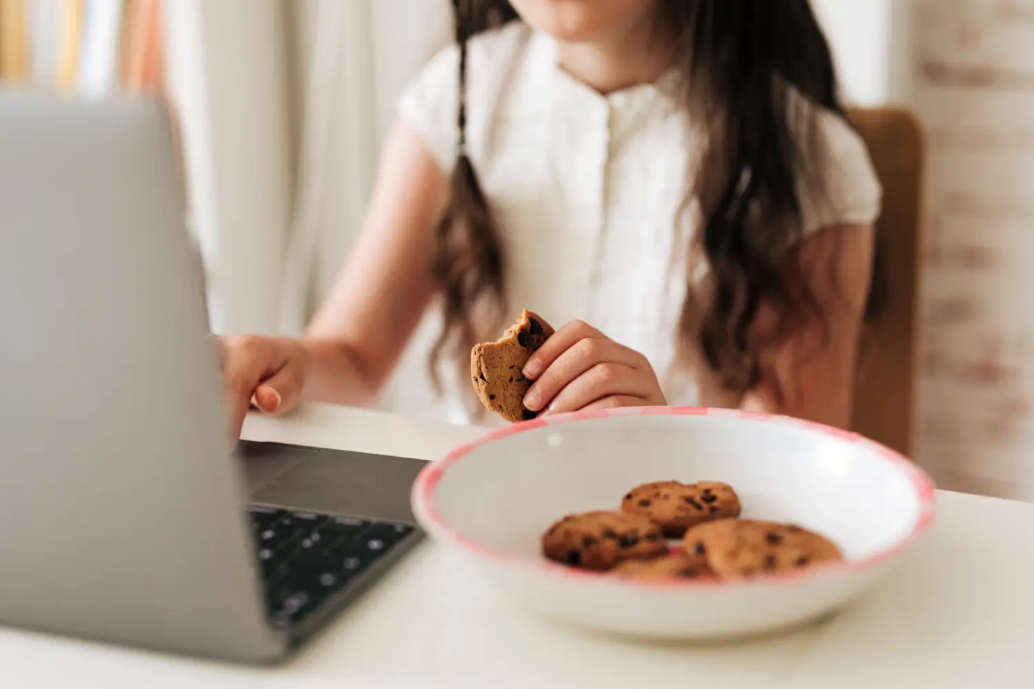 Žena hledá informace na internetu a současně jí sušenky, cookies.