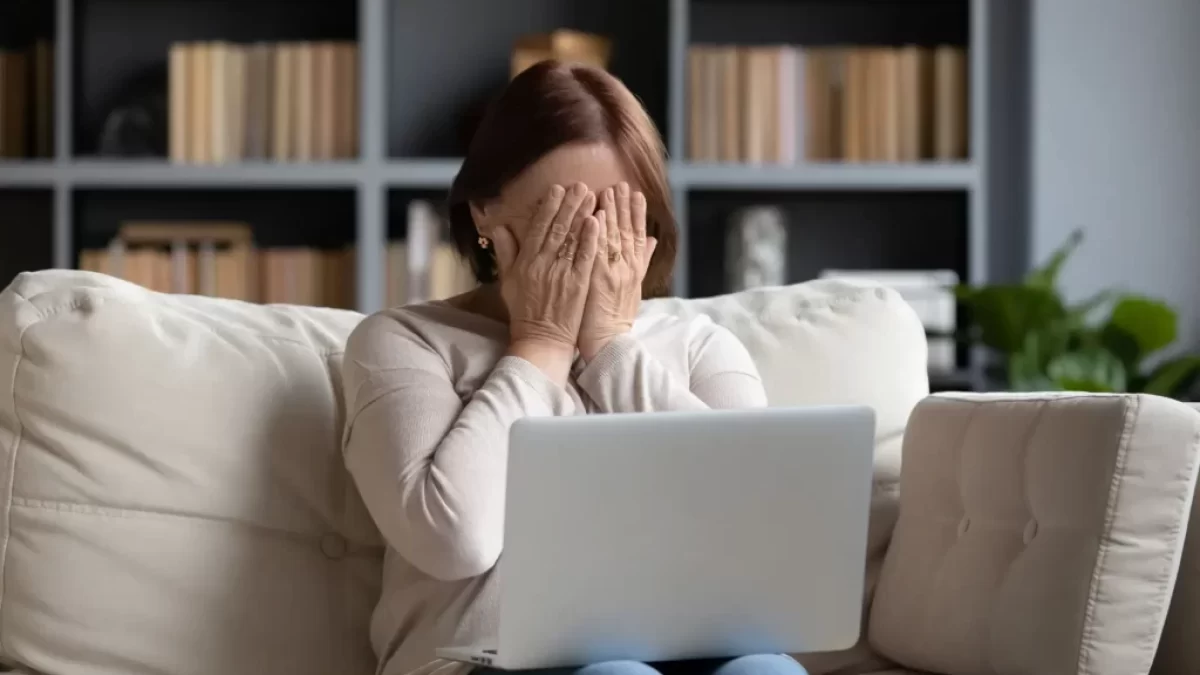 Žena před notebookem s rukama před obličejem