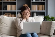 Žena před notebookem s rukama před obličejem
