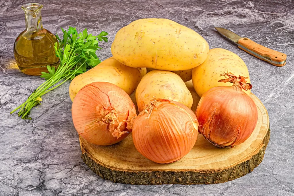 Shutterstock_2397075109 - ByznysDeník Cibule vedle brambor na dřevěné desce