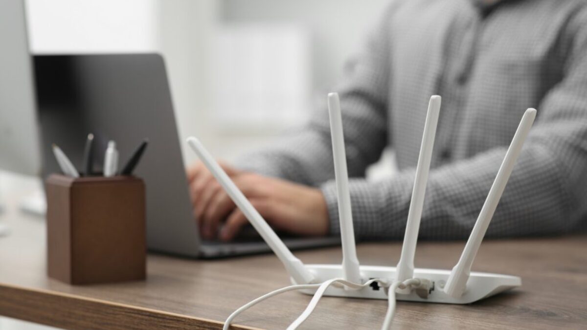 Router se čtyřmi anténami a člověkem v pozadí, zdroj: Shutterstock