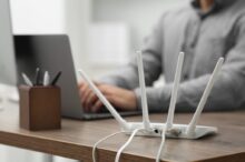 Router se čtyřmi anténami a člověkem v pozadí, zdroj: Shutterstock