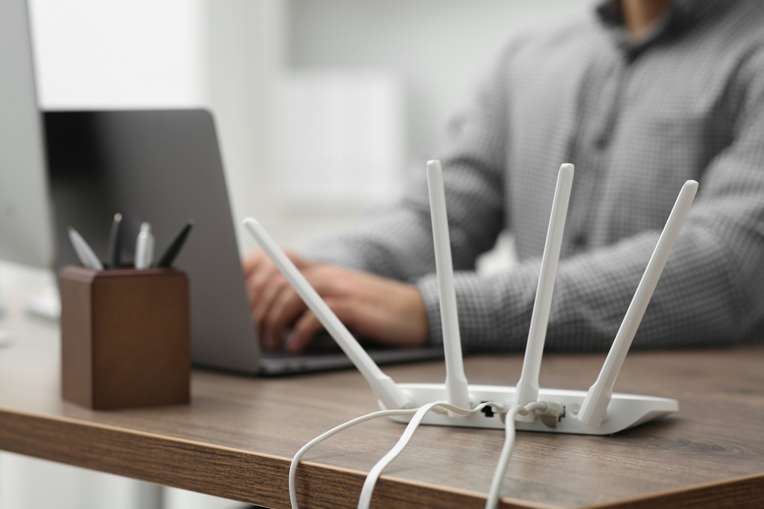 Router se čtyřmi anténami a člověkem v pozadí, zdroj: Shutterstock