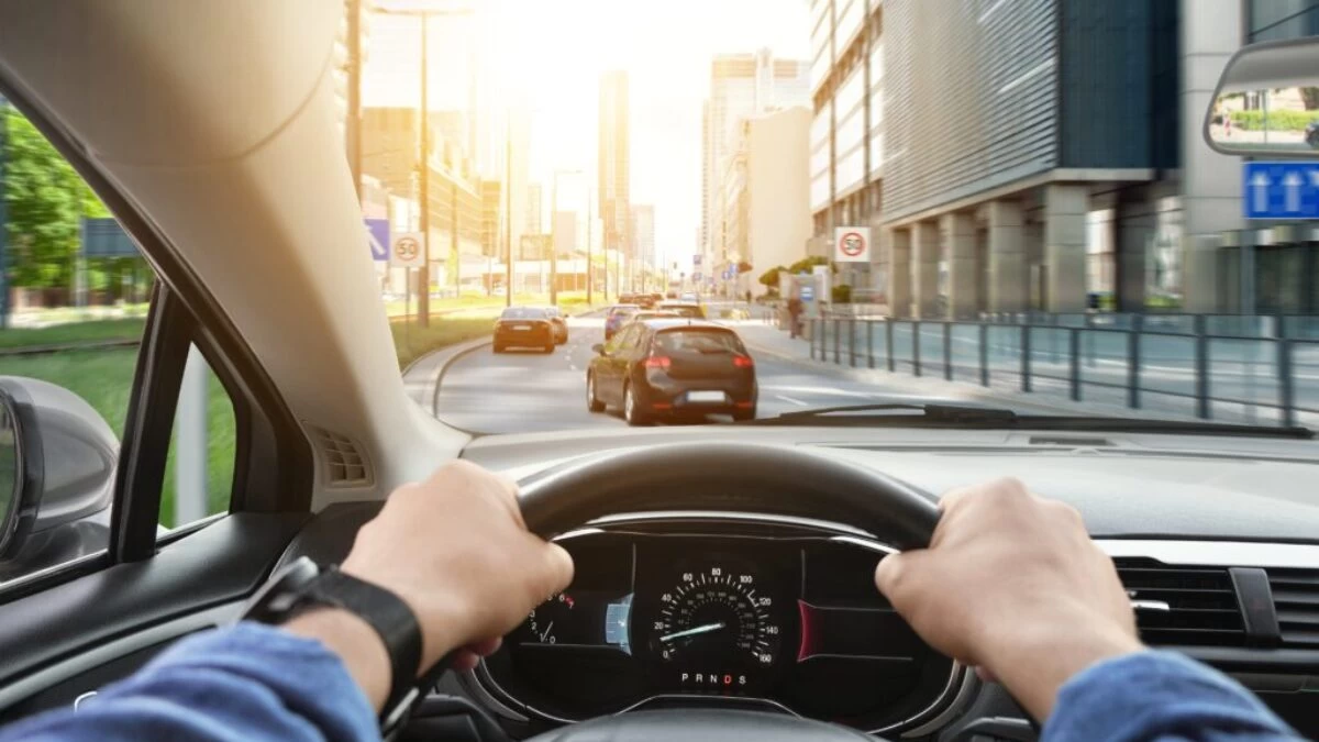 Muž řídí motorové vozidlo a drží volant