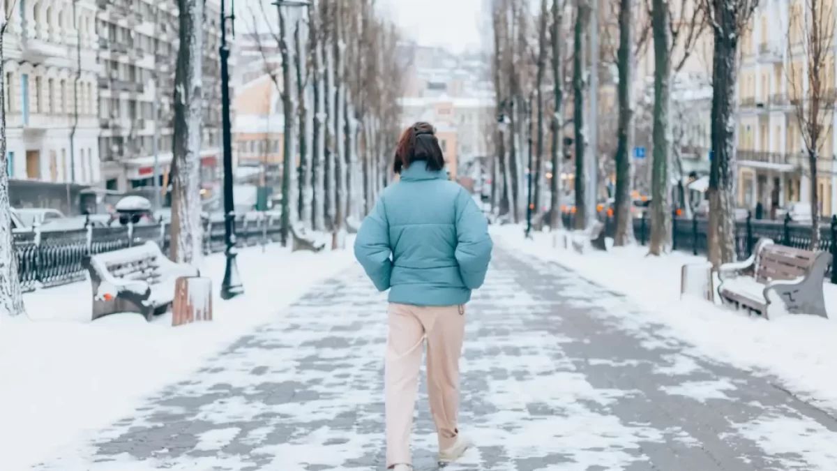 Žena jde mrazivou ulicí.