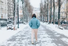Žena jde mrazivou ulicí.