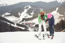 Matka s dcerou lyžuje v horském středisku.