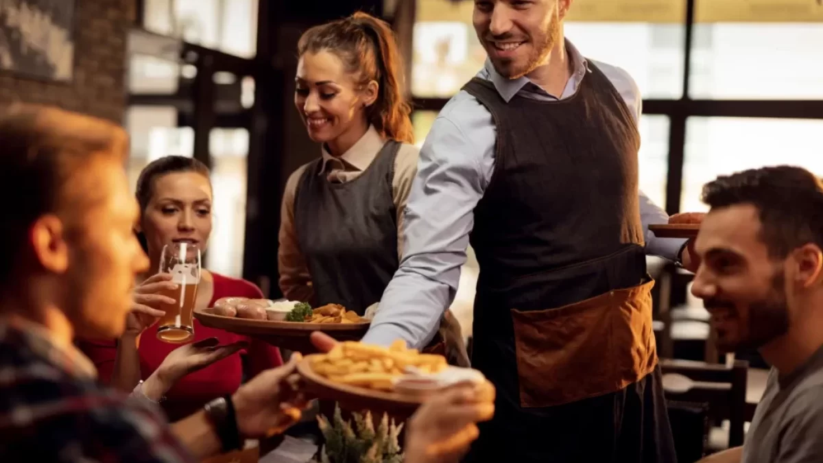 Číšníci dávající hostům objednaná jídla