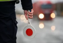 Dopravní policista se zastavovacím terčem provádí silniční kontrolu.