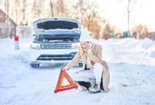 Žena umísťující výstražný trojúhelník před auta v zimě