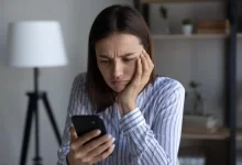 Frustrovaná žena sledující svůj telefon