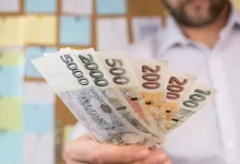 Muž ukazuje české bankovky