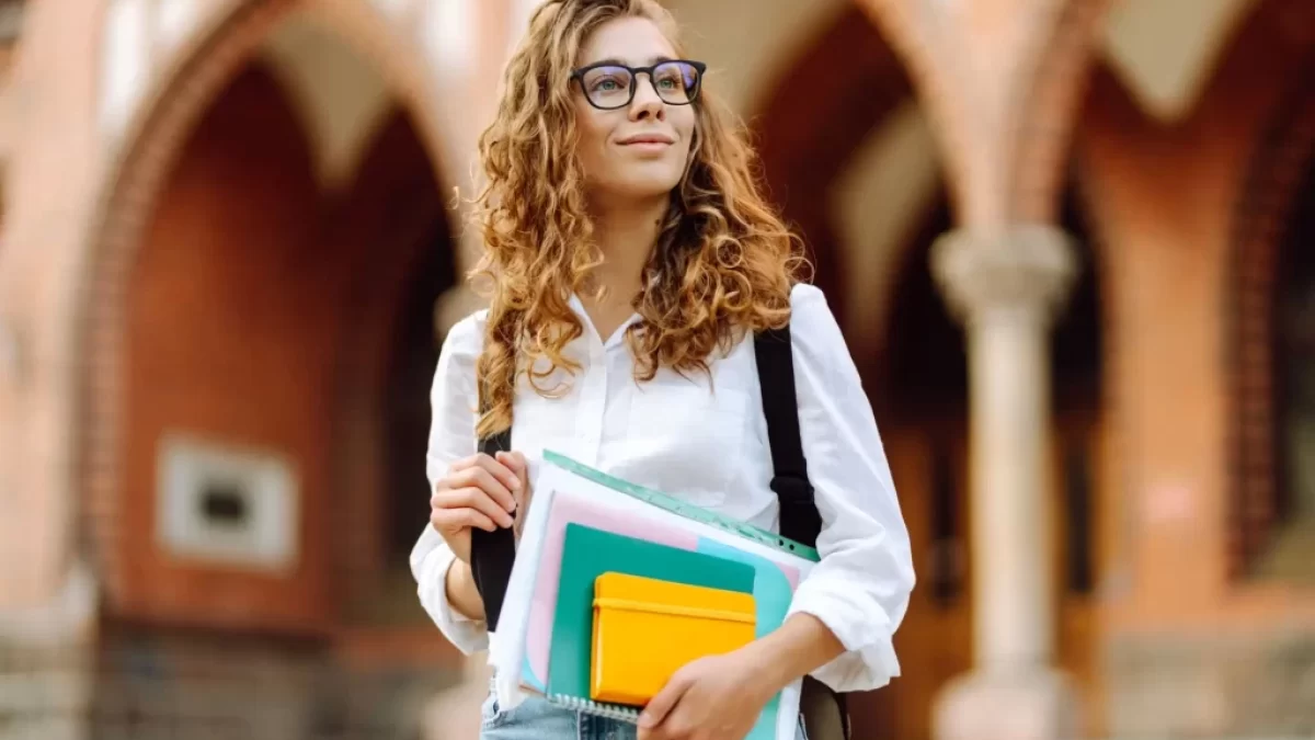 Studentka s kudrnatými vlasy držící knihy