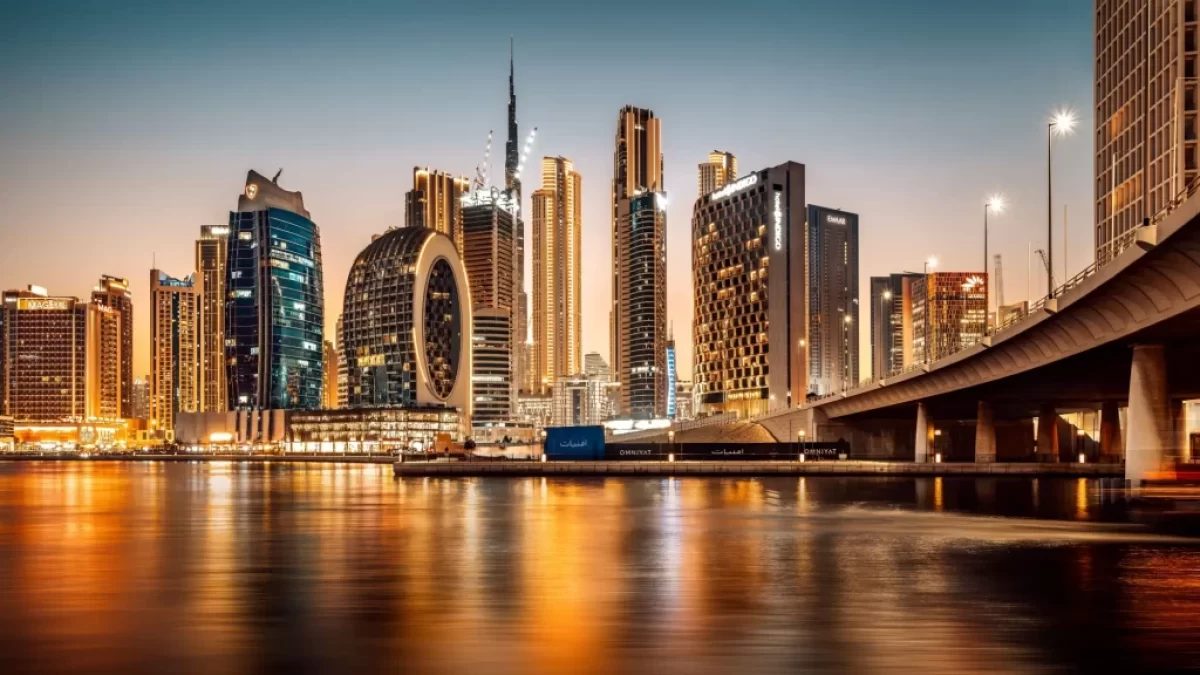 Noční pohled na futuristické panorama Dubaje s rozsvícenými mrakodrapy a odrazem ve vodní hladině.