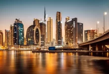 Noční pohled na futuristické panorama Dubaje s rozsvícenými mrakodrapy a odrazem ve vodní hladině.
