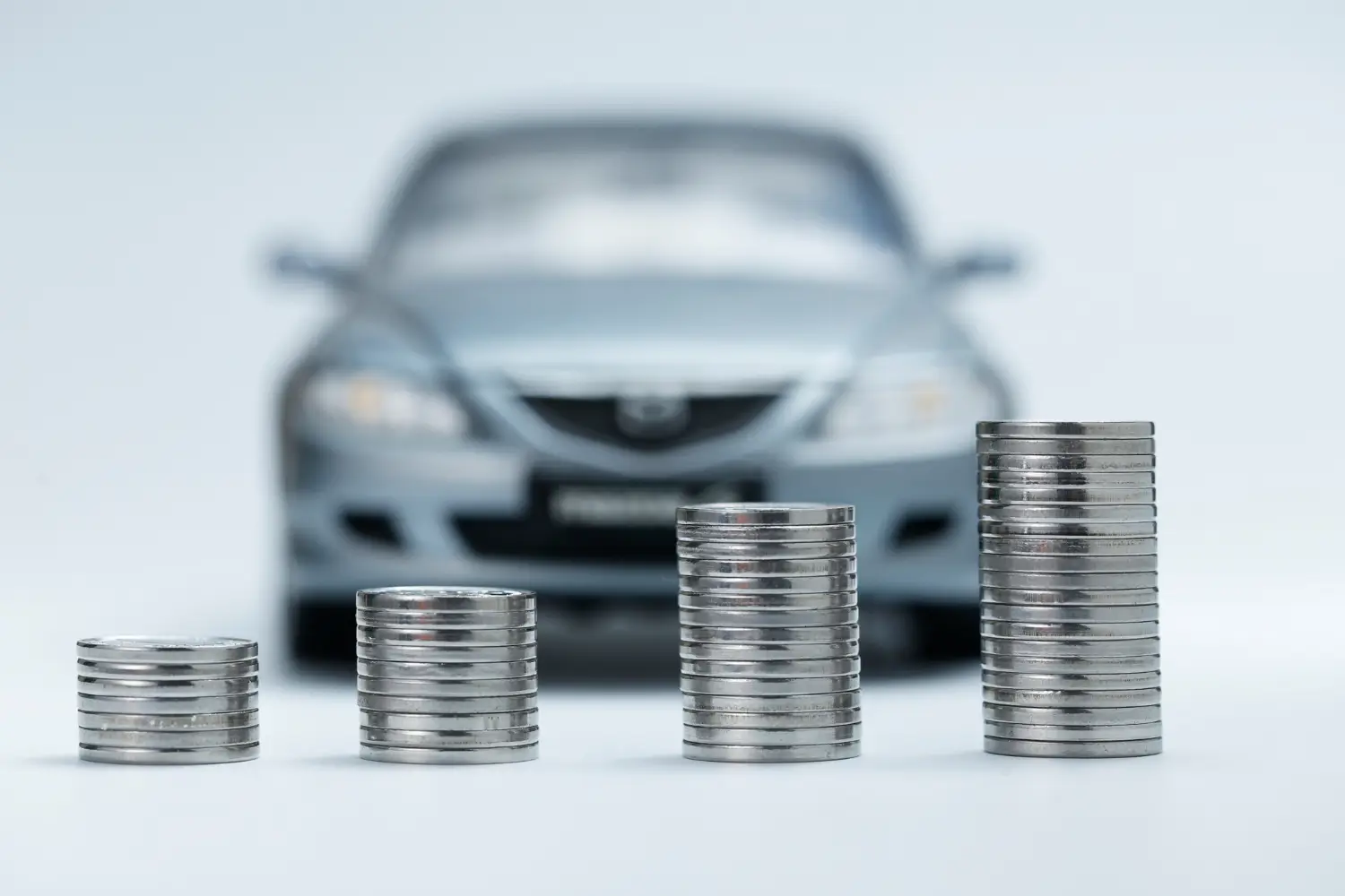 Vpředu jsou mince a v pozadí se nachází auto.