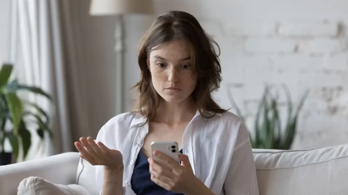 Divící se žena nad mobilním telefonem