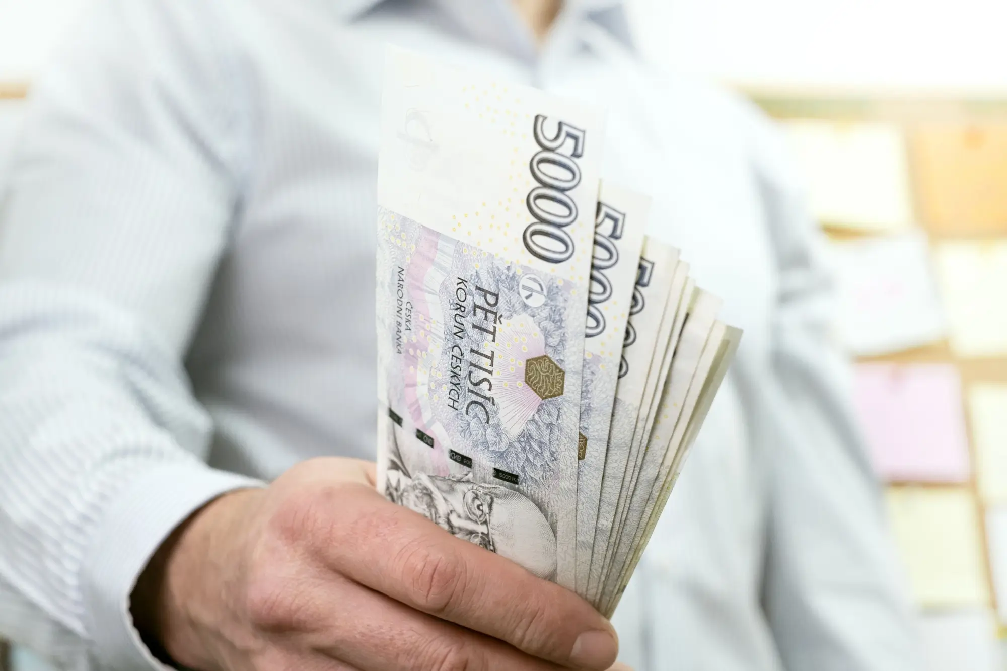 Shutterstock_2255055797 - ByznysDeník Muž s bankovkami v hodnotě 5 000 Kč