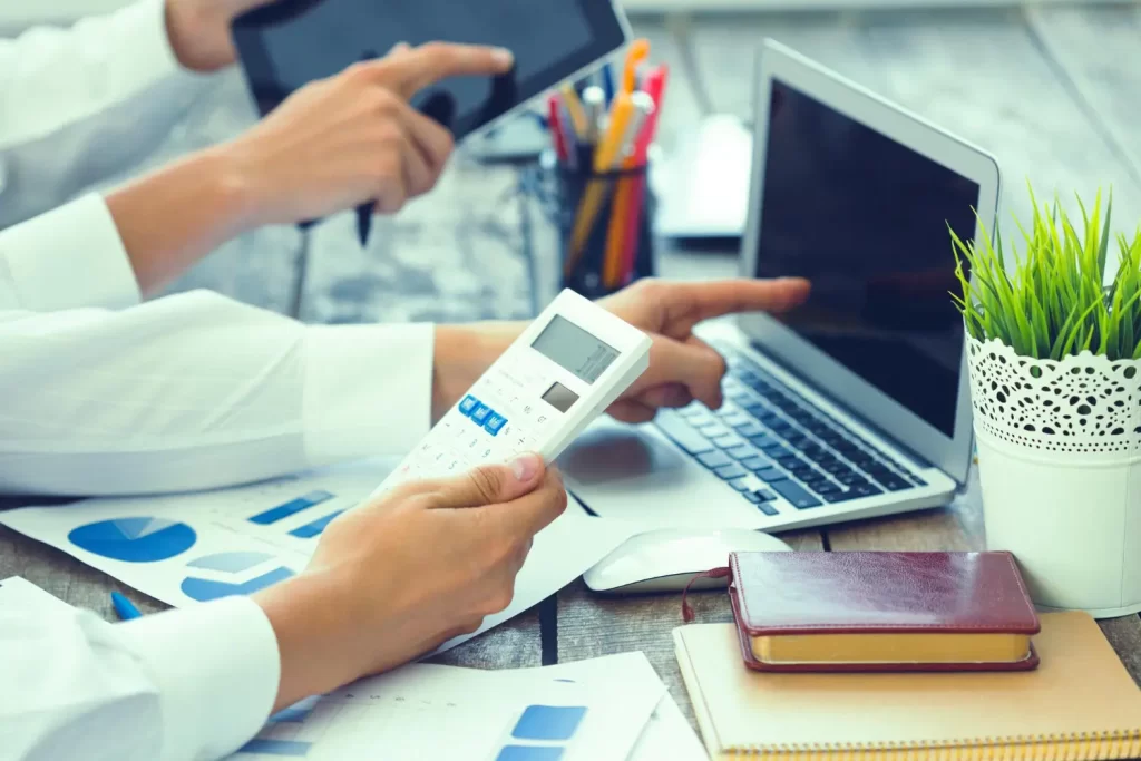 Vyberte si výhodný účet pro své peníze. - ByznysDeník Lidé drží kalkulačku a počítají finance.