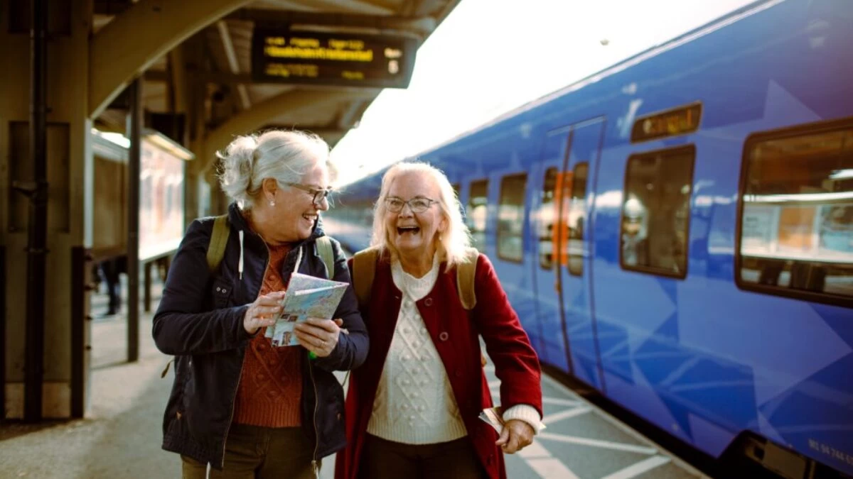 Dvě kamarádky seniorky čekají na nádraží na vlak a užívají si výlet