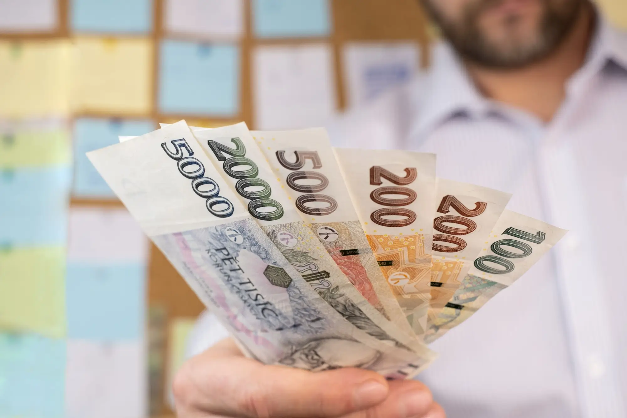 Muž dávající české bankovky