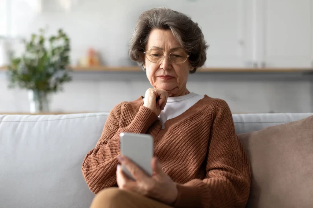 Shutterstock_2419332759 - ByznysDeník Seniorka se dívá na telefon