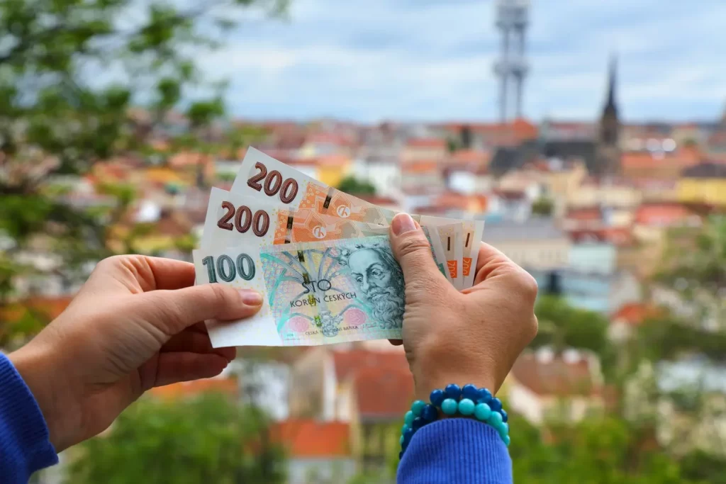 U nás je zatím oficiální měnou česká koruna - ByznysDeník Osoba drží české bankovky.