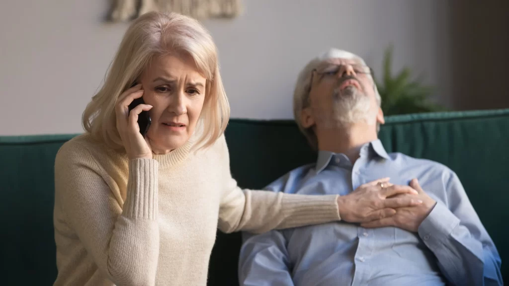Pozor si dejte i na infarkt. Zdroj: Shutterstock - ByznysDeník Žena, která volá záchranku muži, kterého bolí na hrudi.