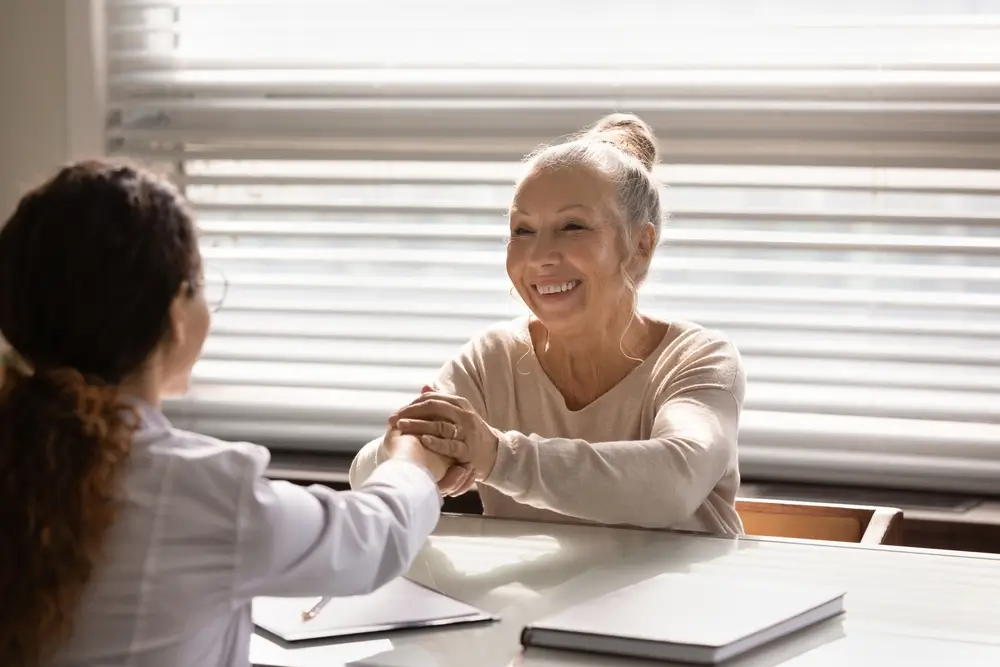 Tchyně narozené ve znamení Ryby jsou velmi empatické. Zdroj: Shutterstock. - ByznysDeník Starší žena objímá dlaněmi ruku mladší ženy.