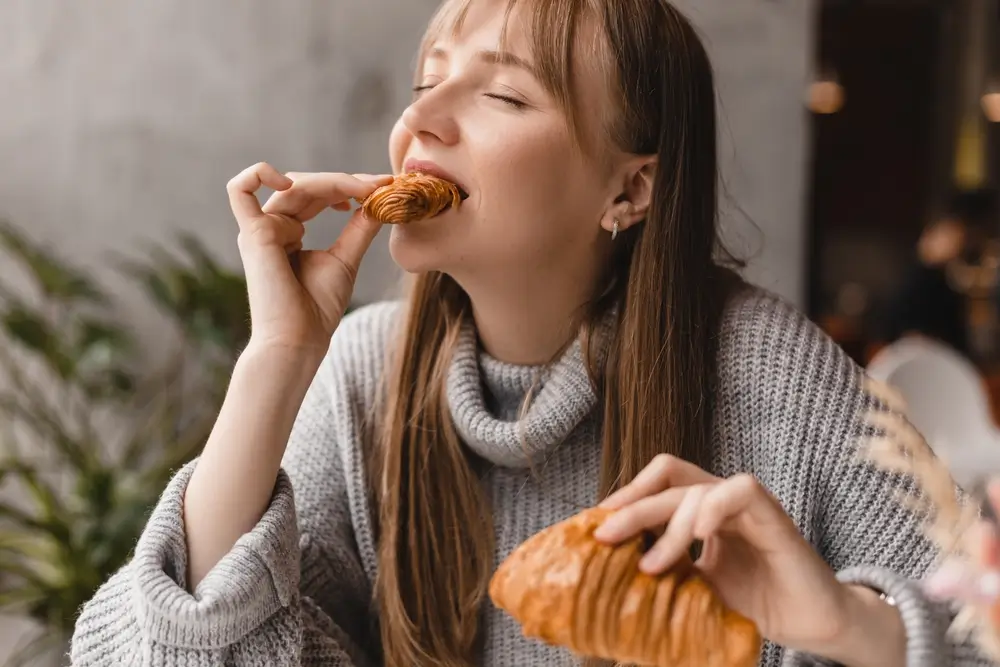 shutterstock_2299982201 - ByznysDeník Žena jí croissant.