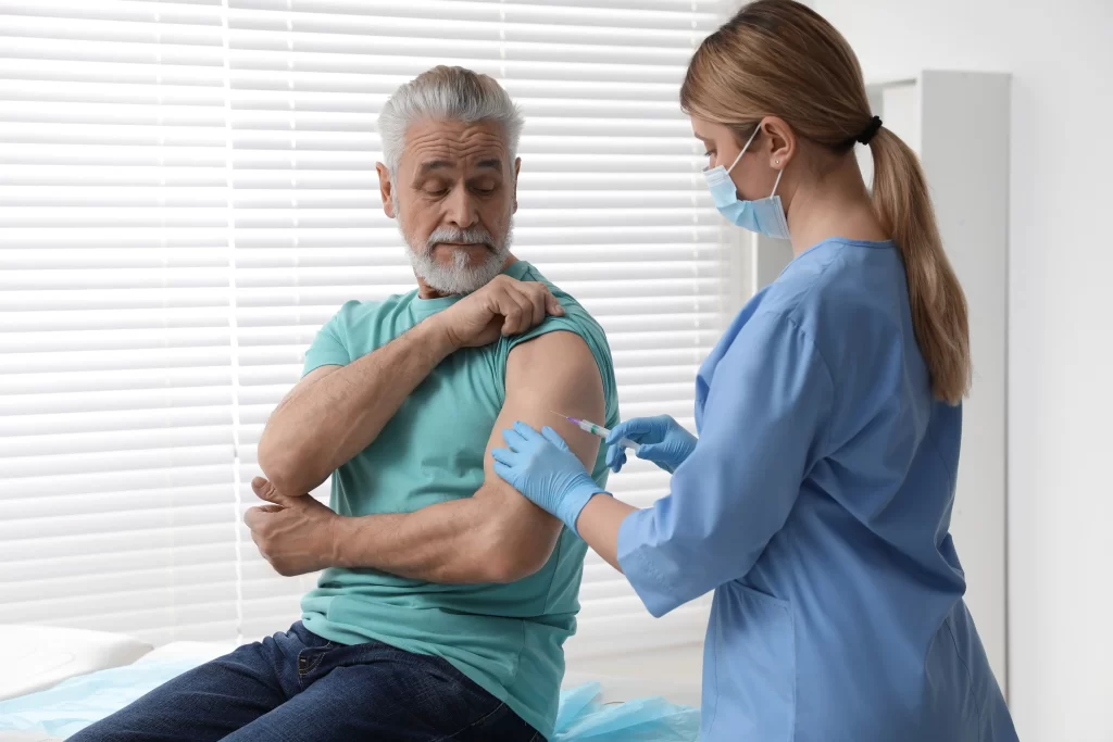 Očkování proti chřipce je seniorům výrazně doporučováno. Zdroj: Shutterstock - ByznysDeník Muž u lékaře, kterému zdravotní sestra dává injekci.