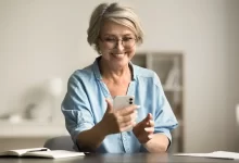 Starší žena se dívá do mobilu.