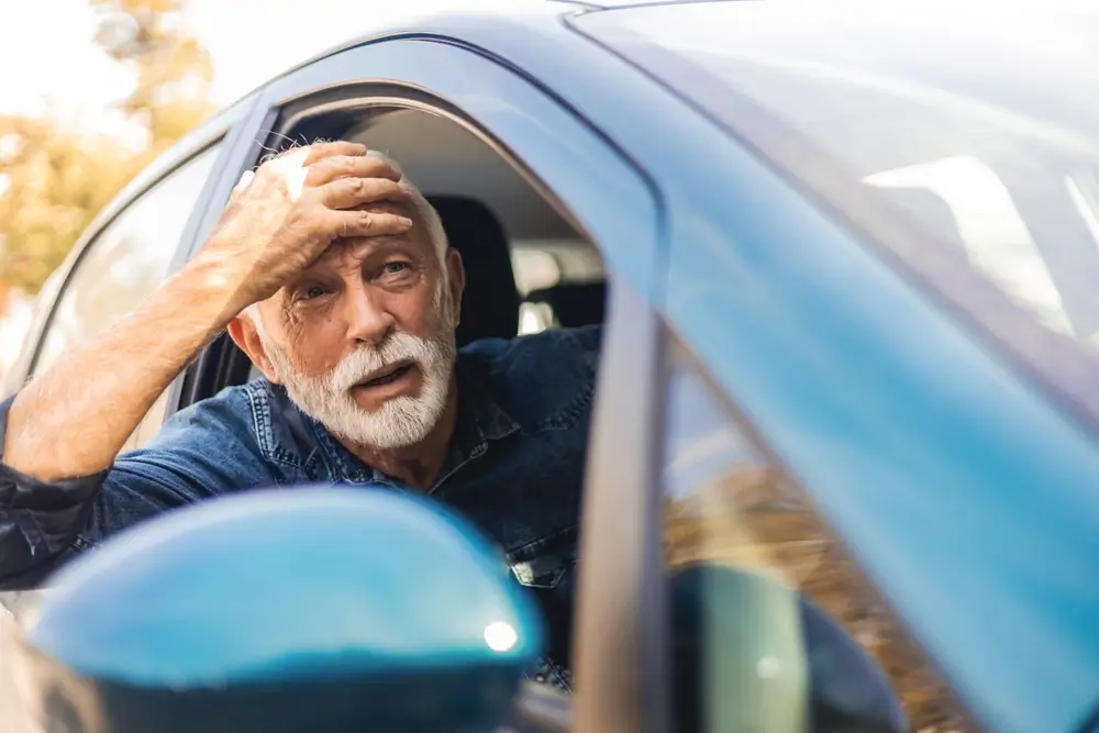 shutterstock_2377556229 - ByznysDeník Muž v pokročilém věku sedí v autě a chytá se za hlavu.