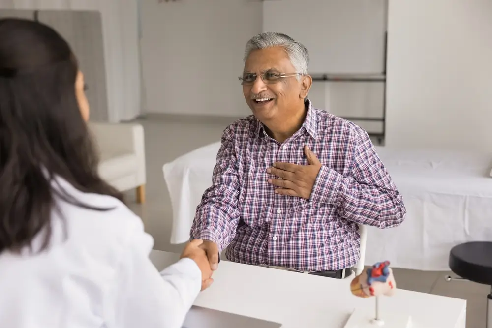 shutterstock_2389637587 - ByznysDeník Muž je u doktorky a drží se za srdce.